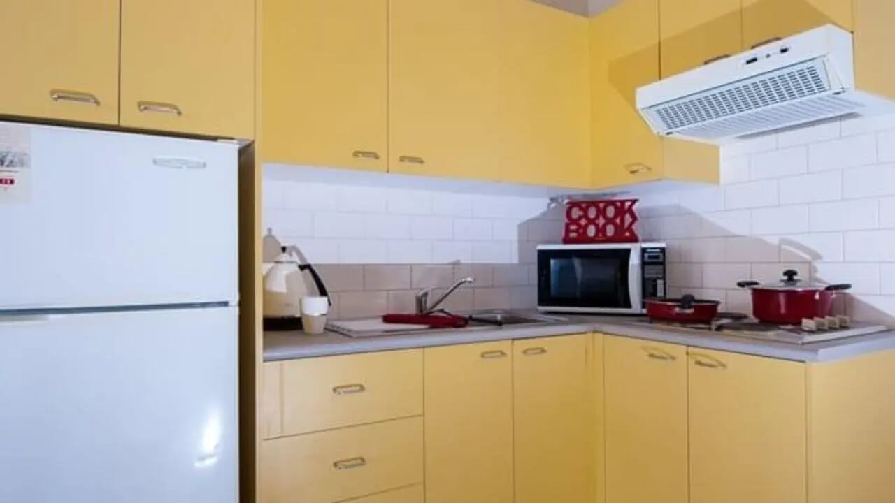 White refrigerator yellow cabinets microwave red pots kitchen at Student Living - 570 Swanston in Melbourne Student Accommodation