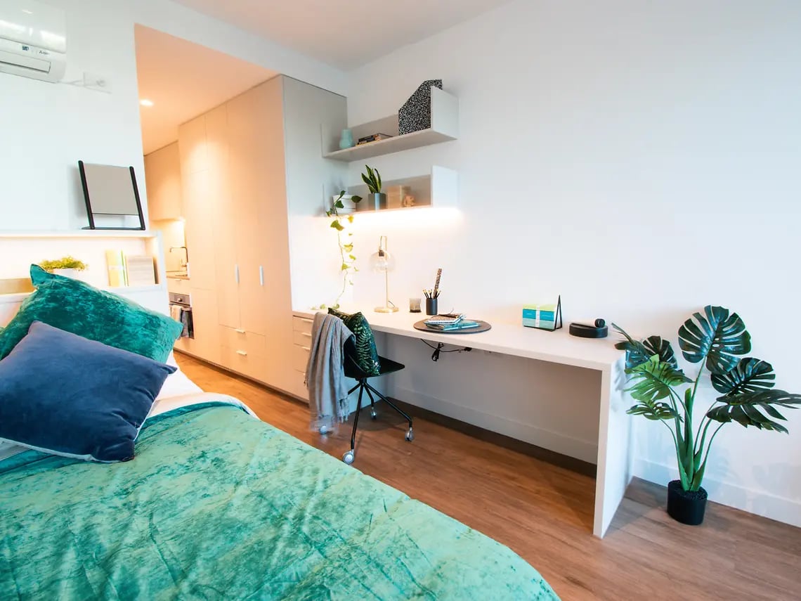 Bed desk closet and plants bedroom area at Yugo Berkeley Street in Melbourne Student Accommodation