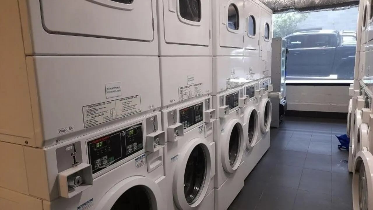 Stacked laundry machines with coin slots and displays laundry room at Student Living on Villiers in Melbourne Student Accommodation