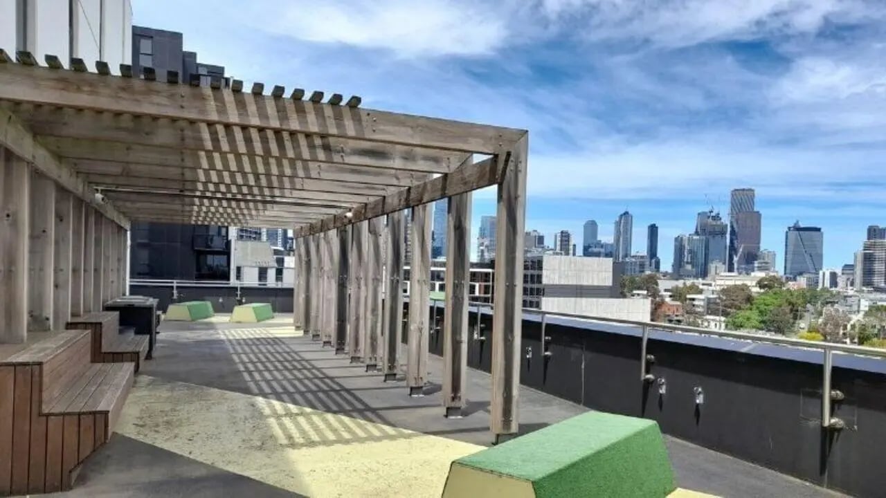 Wooden benches under pergola overlooking city exterior at Student Living on Villiers in Melbourne Student Accommodation