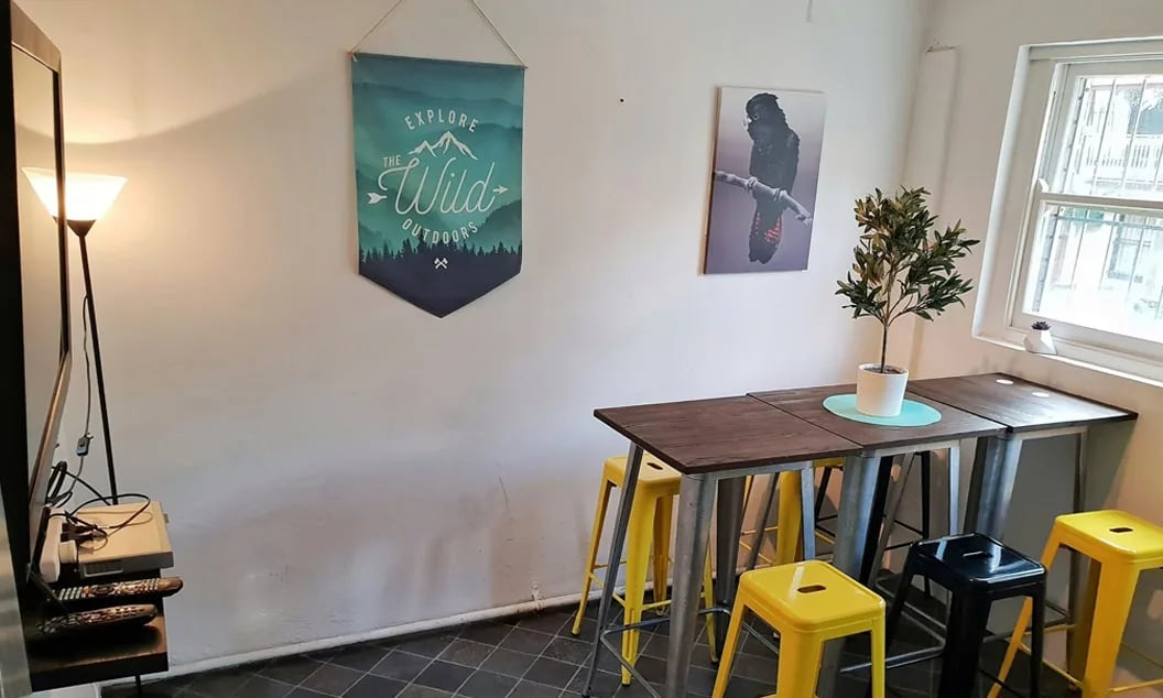 Table with yellow stools and plant kitchen area at ume Hyde Park in Sydney Student Accommodation