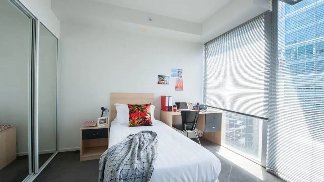 Bed desk wardrobe and mirrored closet bedroom at Student Living on Lonsdale in Melbourne Student Accommodation