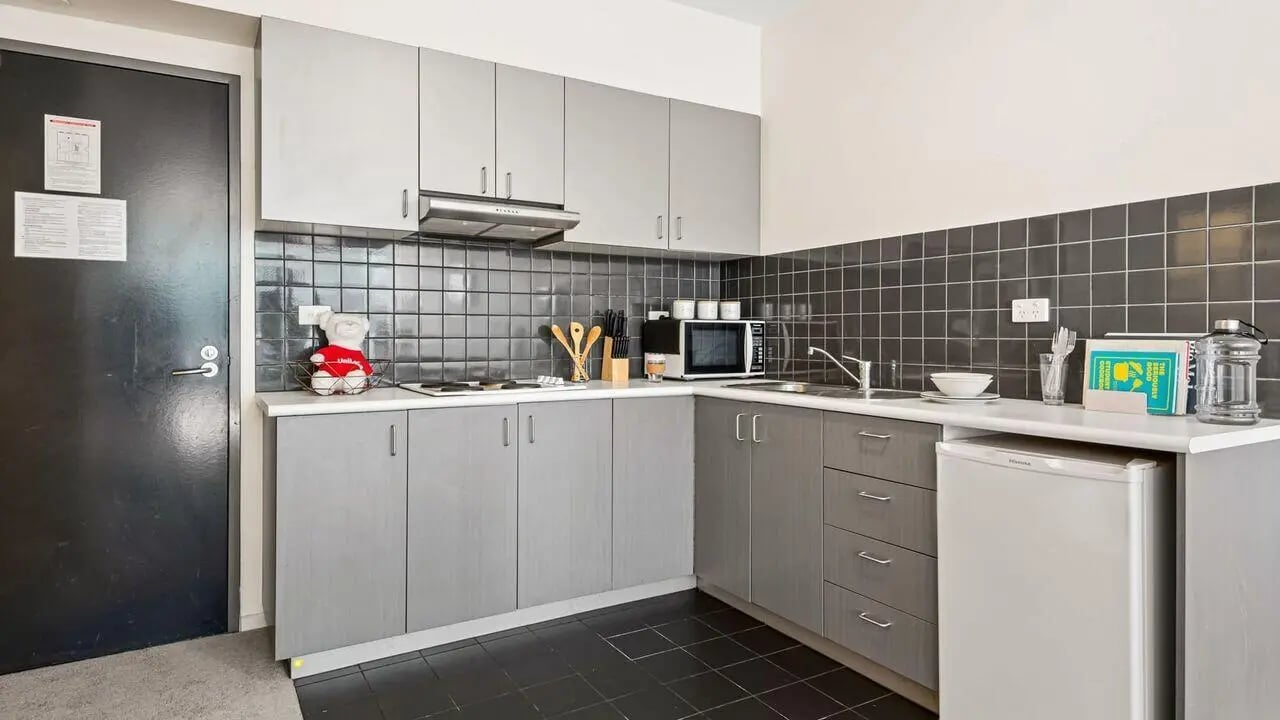 Kitchen with grey cabinets microwave fridge kitchen area at Student Living on Lonsdale in Melbourne Student Accommodation