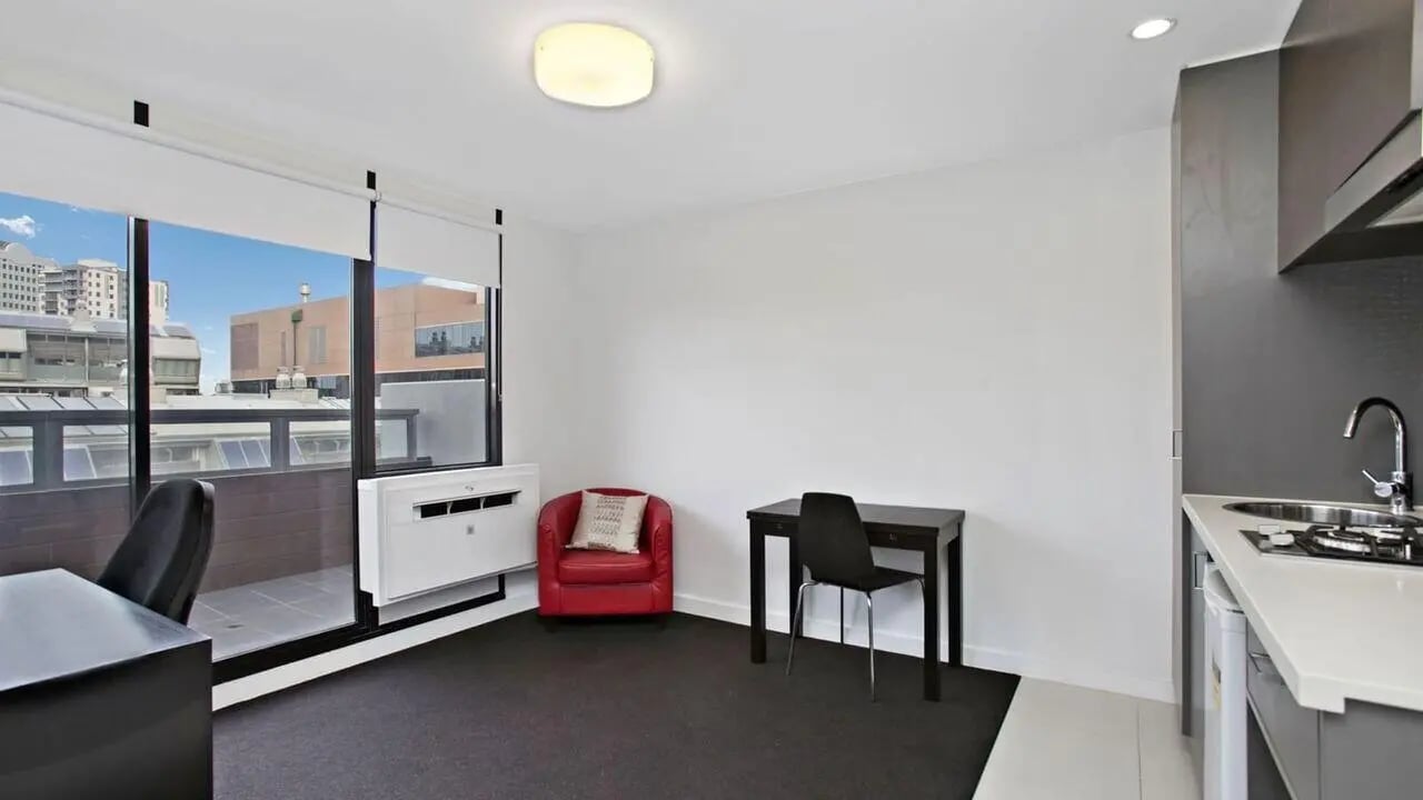 Desk red chair kitchen area living room at Student Living on Raleigh in Melbourne Student Accommodation