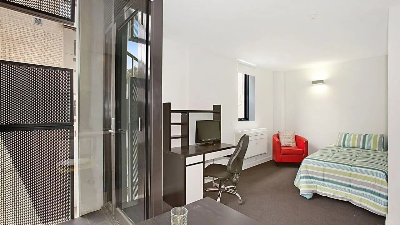Desk bed red chair and monitor study bedroom at Student Living on Raleigh in Melbourne Student Accommodation