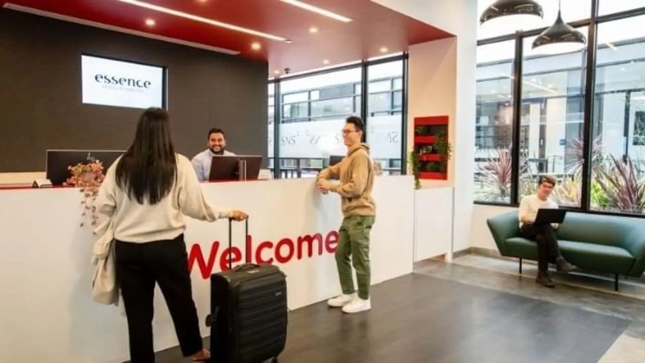 Reception desk welcome sign people luggage lounge area. at UniLodge Carlton in Melbourne Student Accommodation