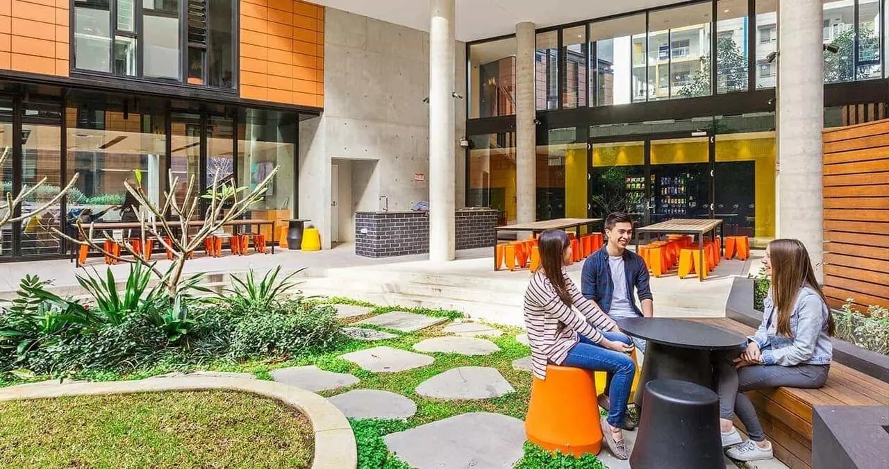 Students chatting at tables and benches outdoor area at Iglu Chatswood in Sydney Student Accommodation