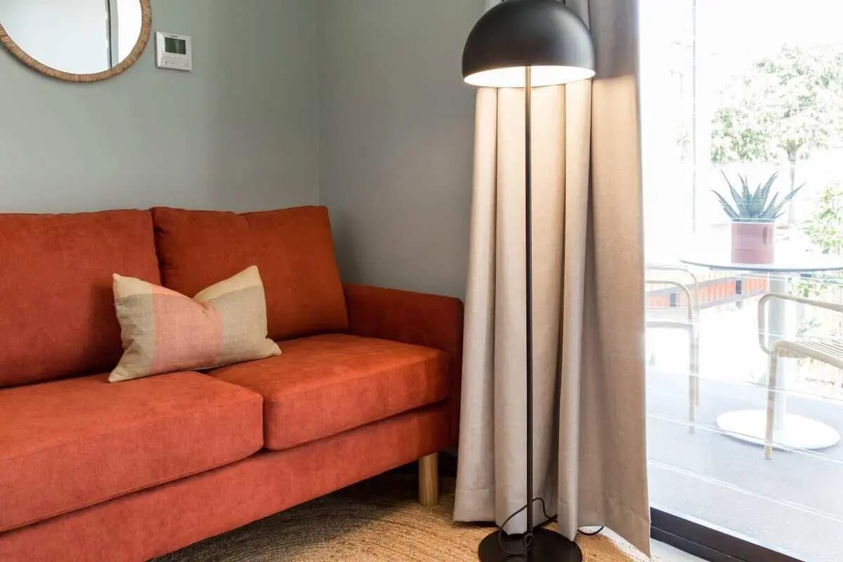 Orange sofa with pillow floor lamp living room at UKO Marrickville Village in Sydney Student Accommodation