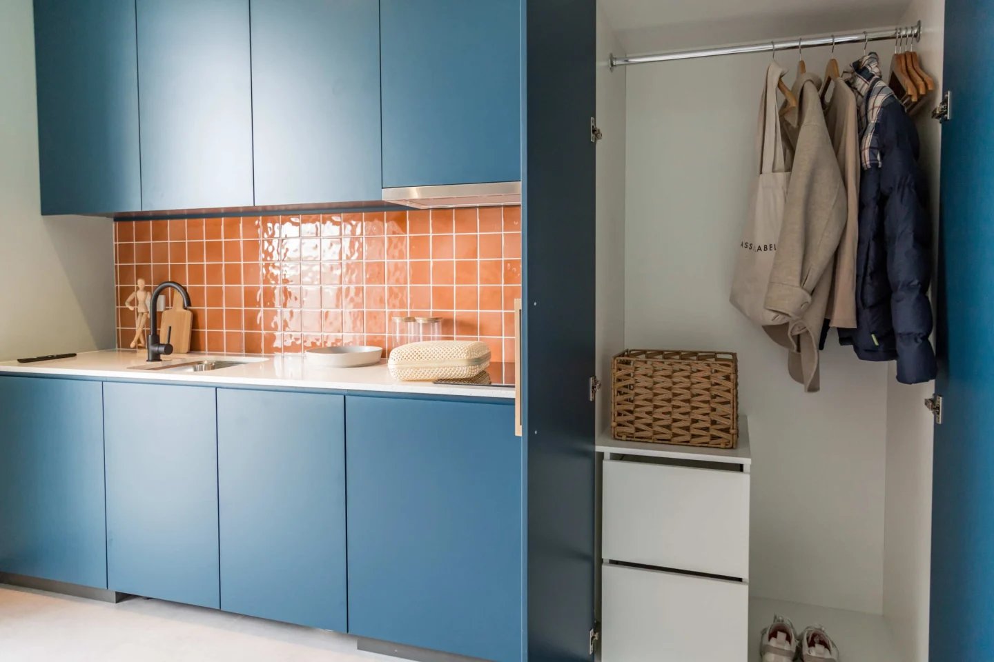 Blue cabinets sink orange tiles clothes closet kitchen at UKO Marrickville Village in Sydney Student Accommodation