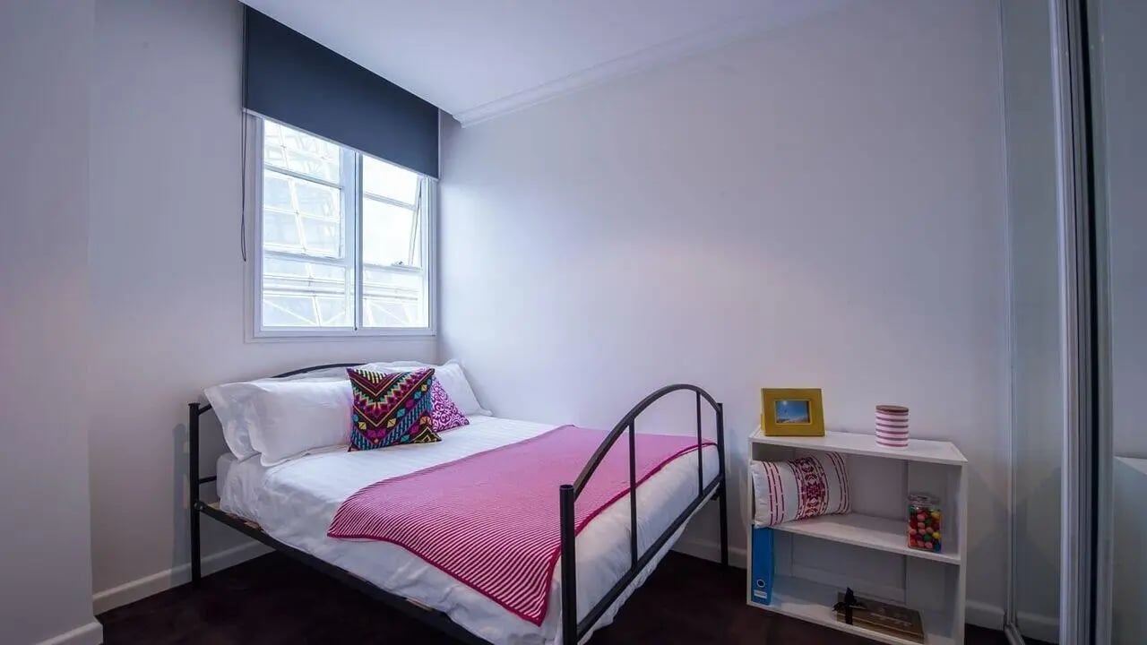 Bed with pink throw colorful pillow bookshelf bedroom at Student Living-339 Swanston in Melbourne Student Accommodation