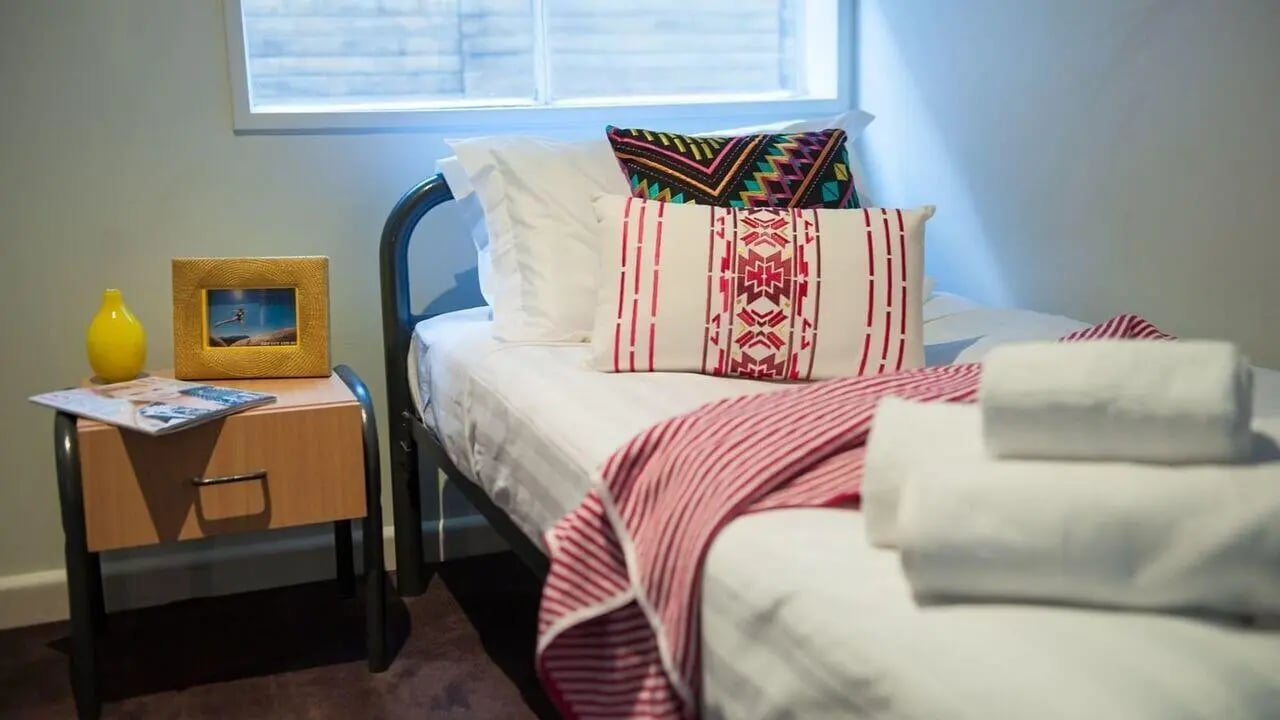 Bed with pillows throws and bedside table Bedroom at Student Living-339 Swanston in Melbourne Student Accommodation