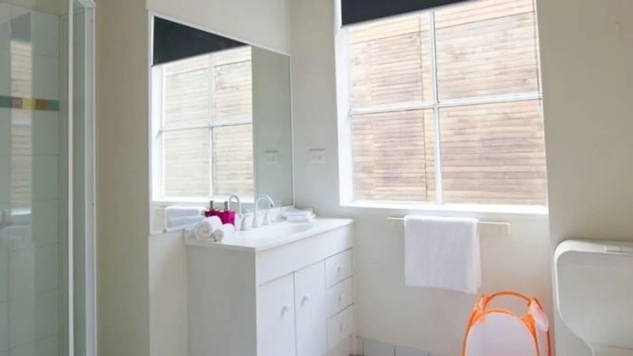Sink shower mirror towels laundry basket bathroom at Student Living-339 Swanston in Melbourne Student Accommodation