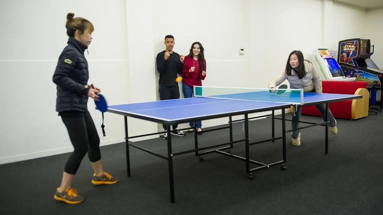 Students playing ping pong near arcade games recreation area at Student Living - 570 Lygon in Melbourne Student Accommodation