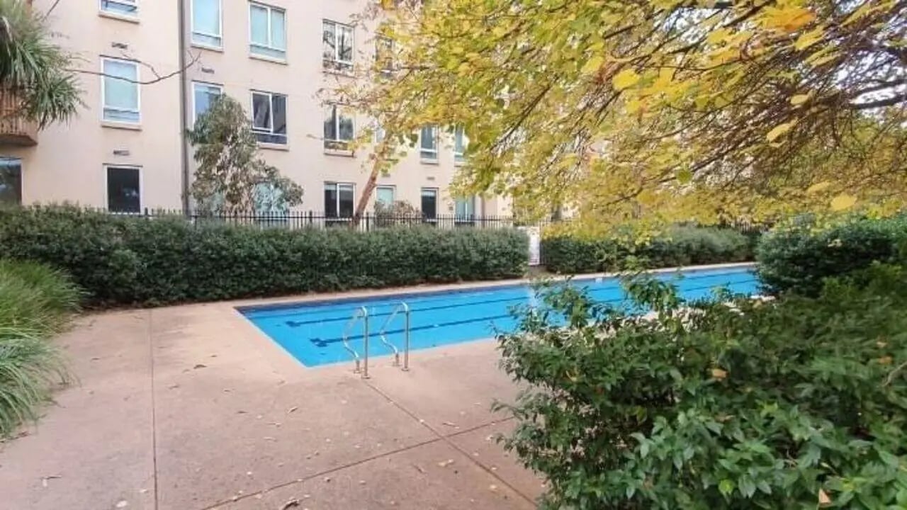 Blue swimming pool with ladders and building exterior at Student Living - 570 Lygon in Melbourne Student Accommodation