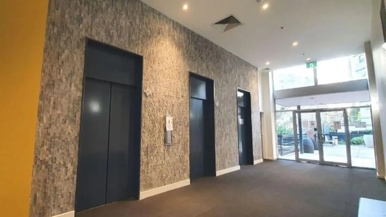 Elevator bank with textured walls and carpeted floor lobby at Student Living - 570 Lygon in Melbourne Student Accommodation
