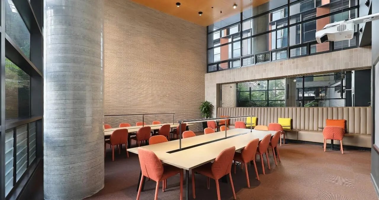Long tables orange chairs built-in seating study area at Iglu Melbourne City in Melbourne Student Accommodation