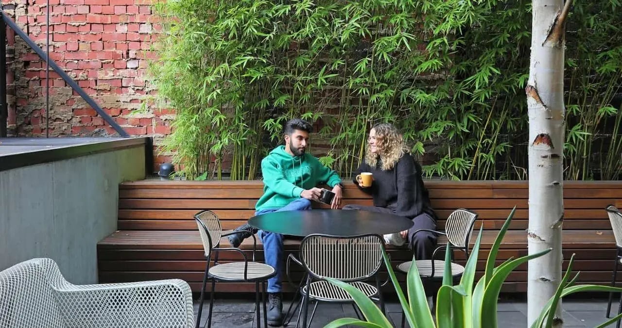 Students sit at a table on wooden bench outdoor area at Iglu Melbourne City in Melbourne Student Accommodation
