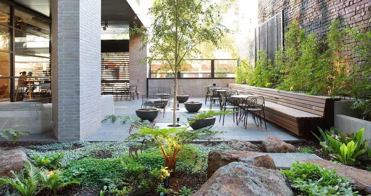 Outdoor seating area with tables chairs and bench exterior at Iglu Melbourne City in Melbourne Student Accommodation