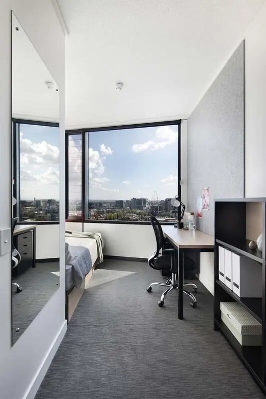 Bed desk chair mirror and city view bedroom at Iglu Melbourne City in Melbourne Student Accommodation