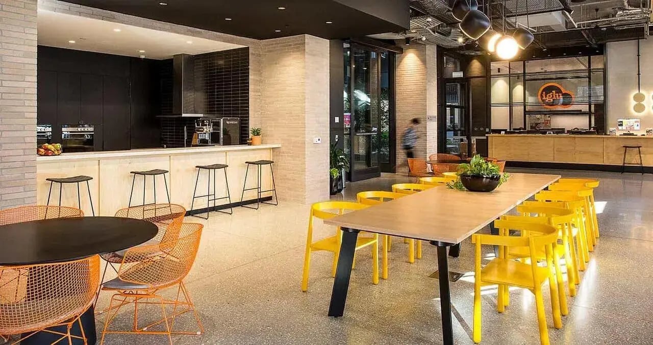 Modern kitchen counter with stools communal dining table and chairs shared space at Iglu Melbourne City in Melbourne Student Accommodation