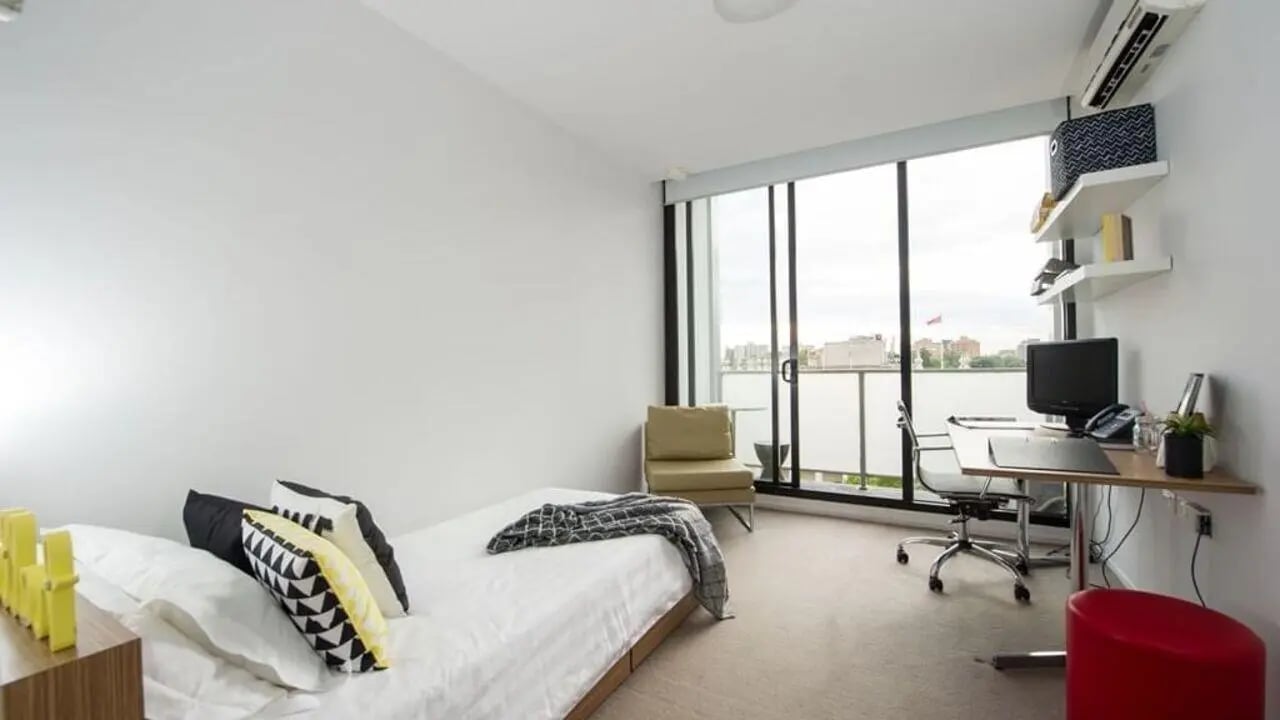 Bed desk chair red ottoman bedroom at Student Living D2 in Melbourne Student Accommodation