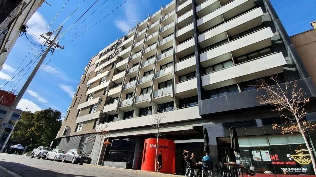 Apartment building with balconies and cafe exterior at Student Living D2 in Melbourne Student Accommodation