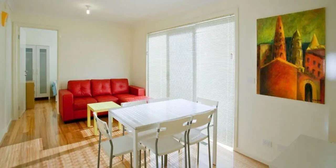 Red sofa dining table and chairs living room at Sunset House in Melbourne Student Accommodation