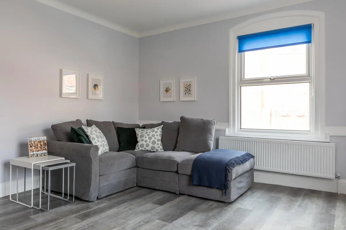 Grey sectional sofa with cushions and blue throw living room at Hyde Park in Leeds Student Accommodation