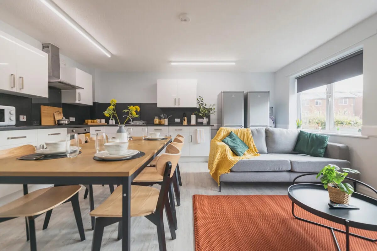 Dining table couch refrigerators kitchen living room at Madison Gardens in Nottingham Student Accommodation