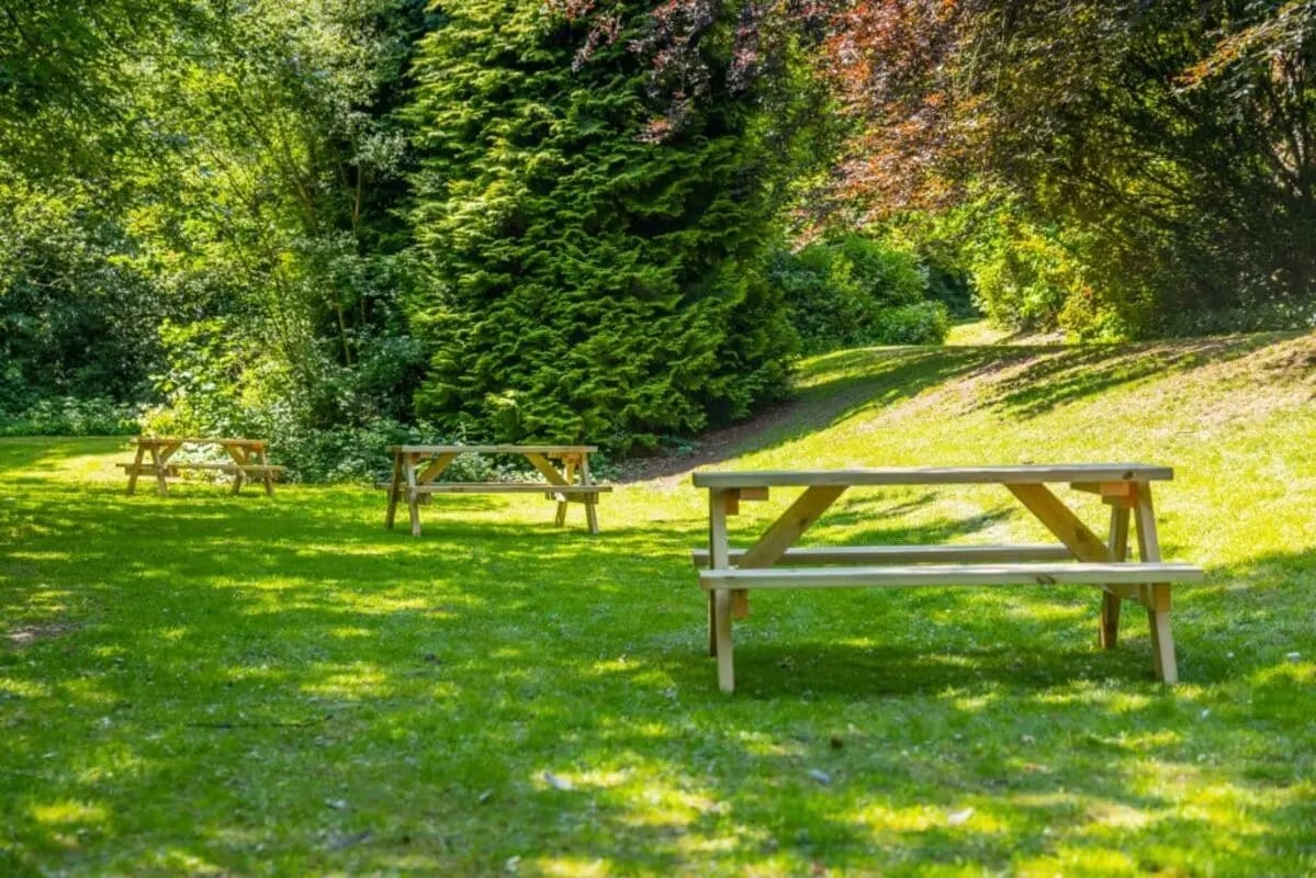 Wooden picnic tables on grassy lawn exterior at Beech Gardens in Birmingham Student Accommodation