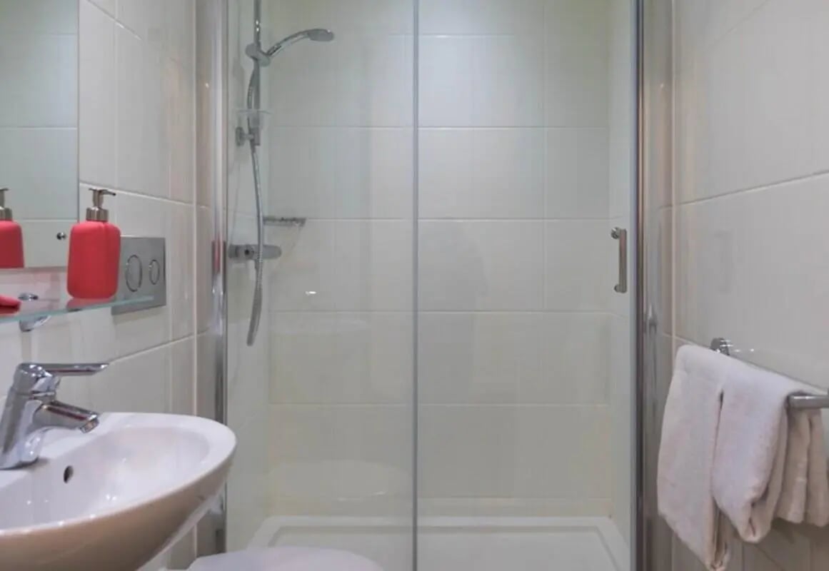 Sink shower with tiled walls and towels bathroom at The Cam Foundry in Cambridge Student Accommodation