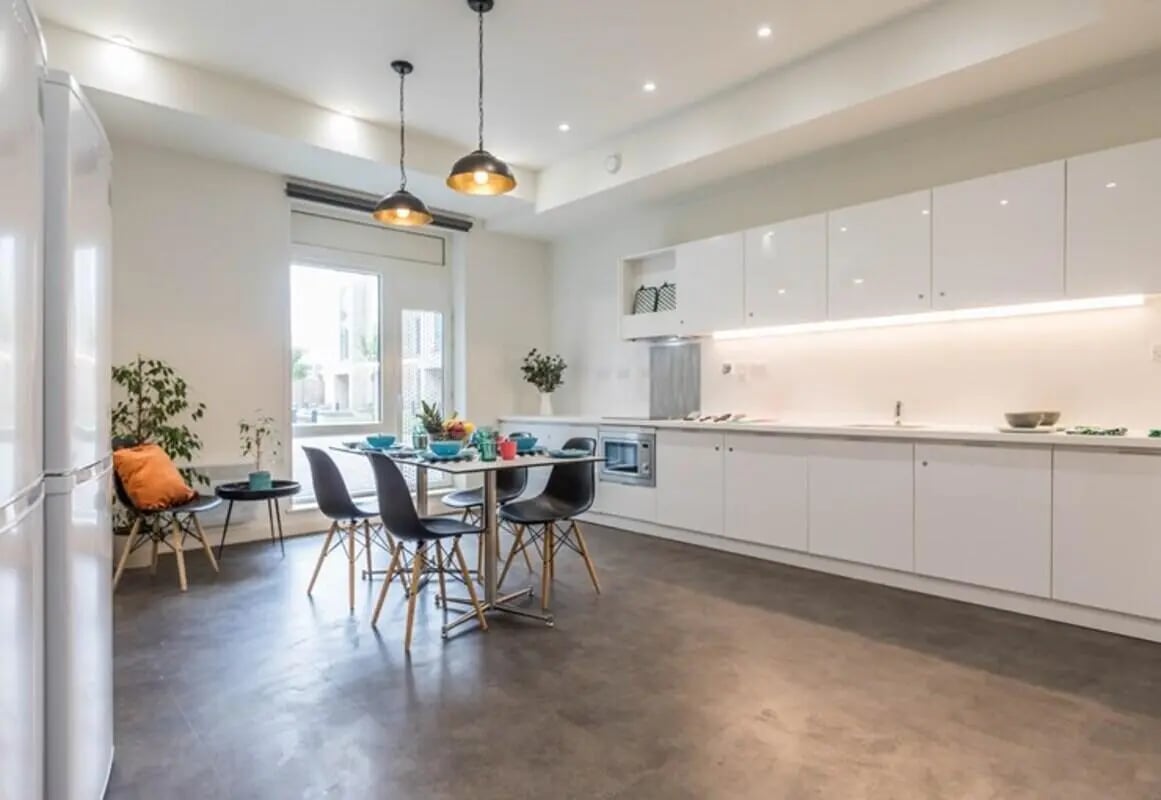 White cabinets dining table with chairs kitchen. at The Cam Foundry in Cambridge Student Accommodation
