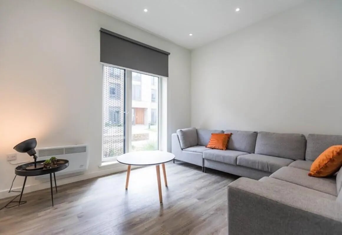 Gray sectional sofa orange pillows small tables living room at The Cam Foundry in Cambridge Student Accommodation