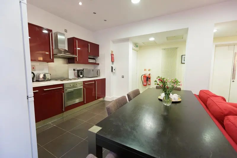 Red cabinets toaster oven fire extinguishers dining table kitchen at AXO Oxford Circus in London Student Accommodation