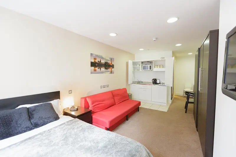Bed kitchen red sofa and wardrobe studio at AXO Oxford Circus in London Student Accommodation