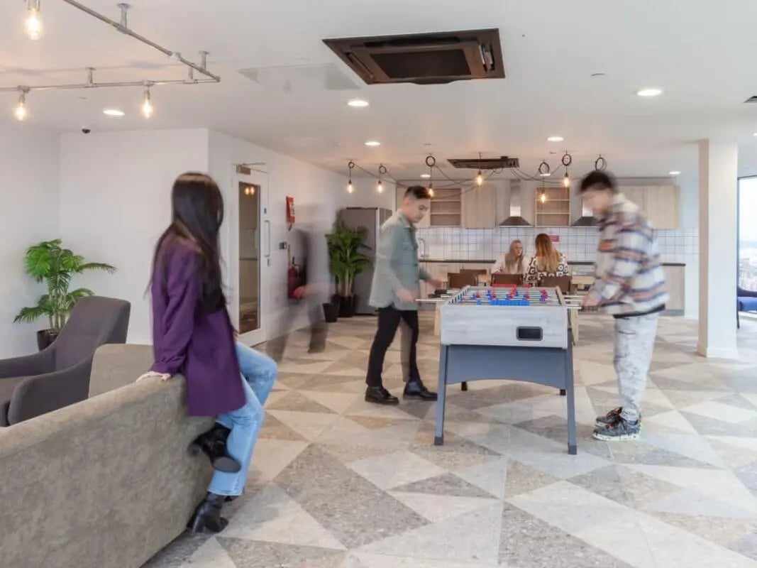 Students playing foosball by kitchen area living room at True Glasgow in Glasgow Student Accommodation