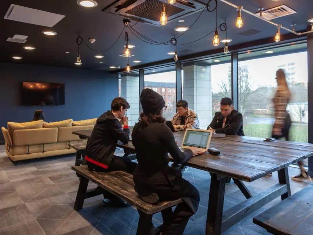 Students study at a table with laptops living room at True Glasgow in Glasgow Student Accommodation