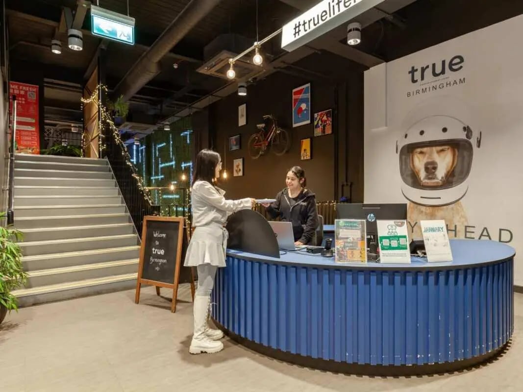 Reception area with students and blue counter at True Birmingham in Birmingham Student Accommodation