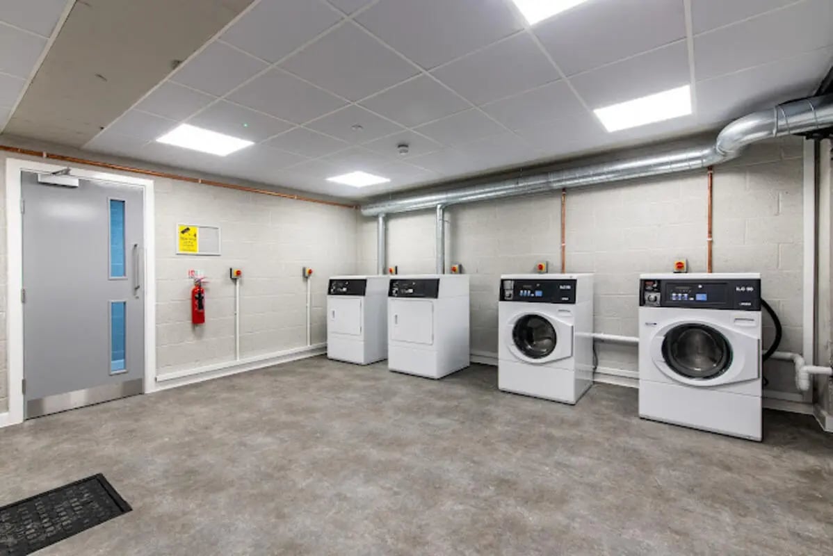 Four washing machines and a fire extinguisher Laundry Room at Broadgate House Student Living in Nottingham Student Accommodation