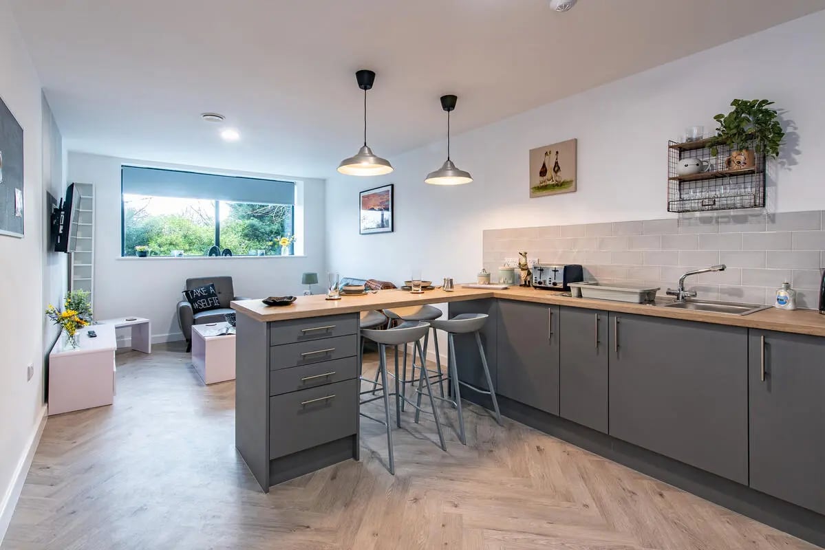 Kitchen with bar stools and living area view Kitchen at Broadgate House Student Living in Nottingham Student Accommodation