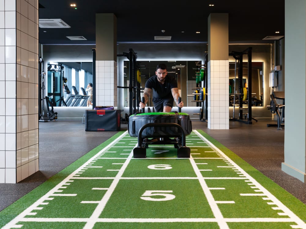 Man pushing tire on turf with gym equipment. Gym. at True Liverpool in Liverpool Student Accommodation