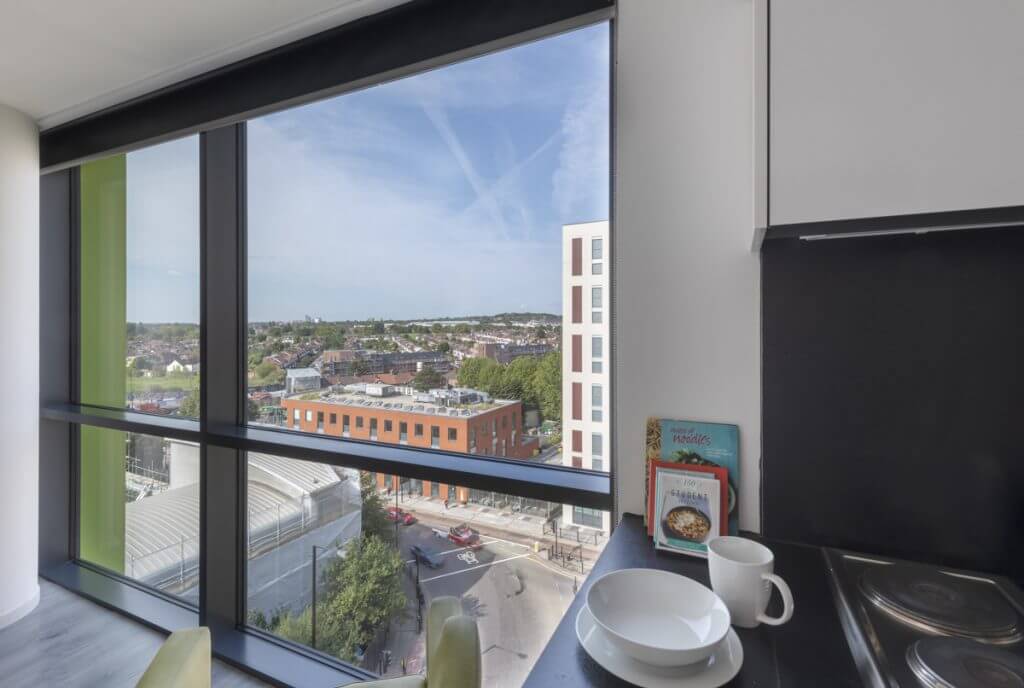 Kitchen with bowls mug books and cityscape view kitchen at The Lyra in London Student Accommodation