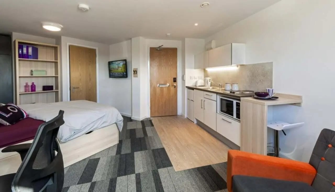 Bed shelving and kitchen with dining area studio at The Railyard Cambridge in Cambridge Student Accommodation