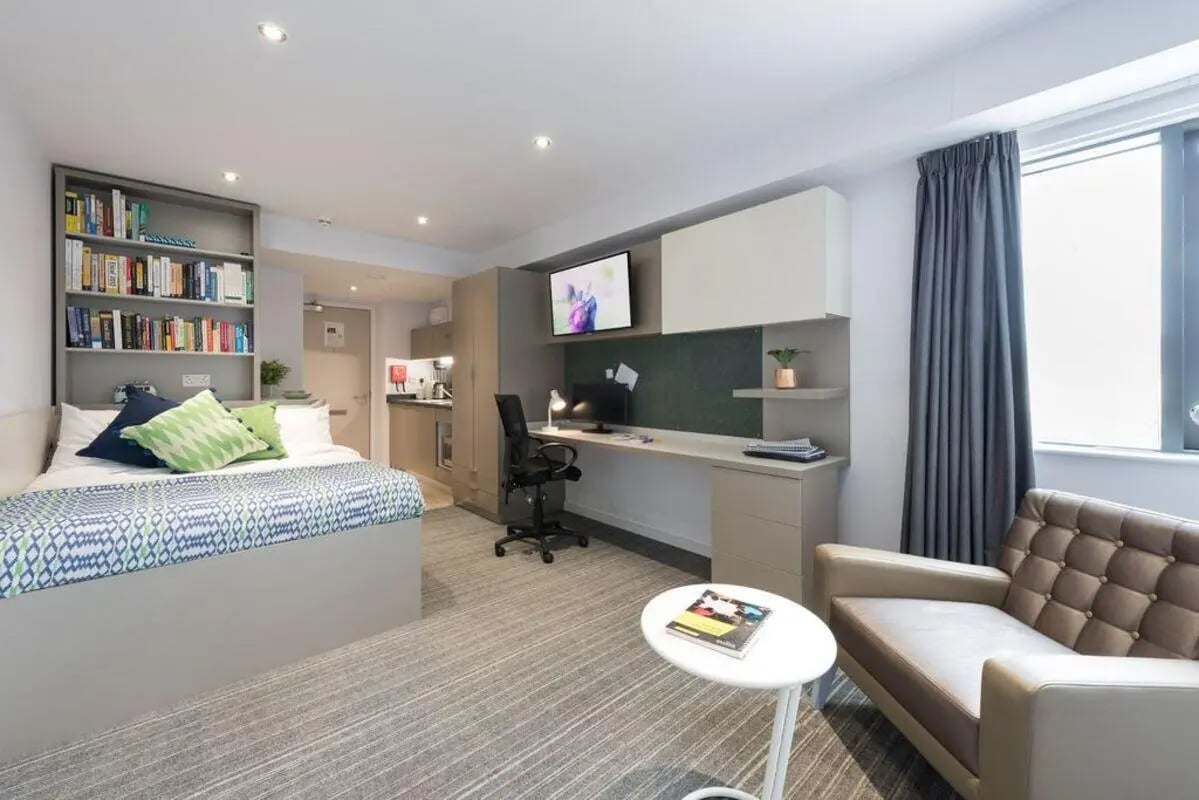 Bed bookshelf desk TV couch and kitchen living area at The Kingfisher in Exeter Student Accommodation