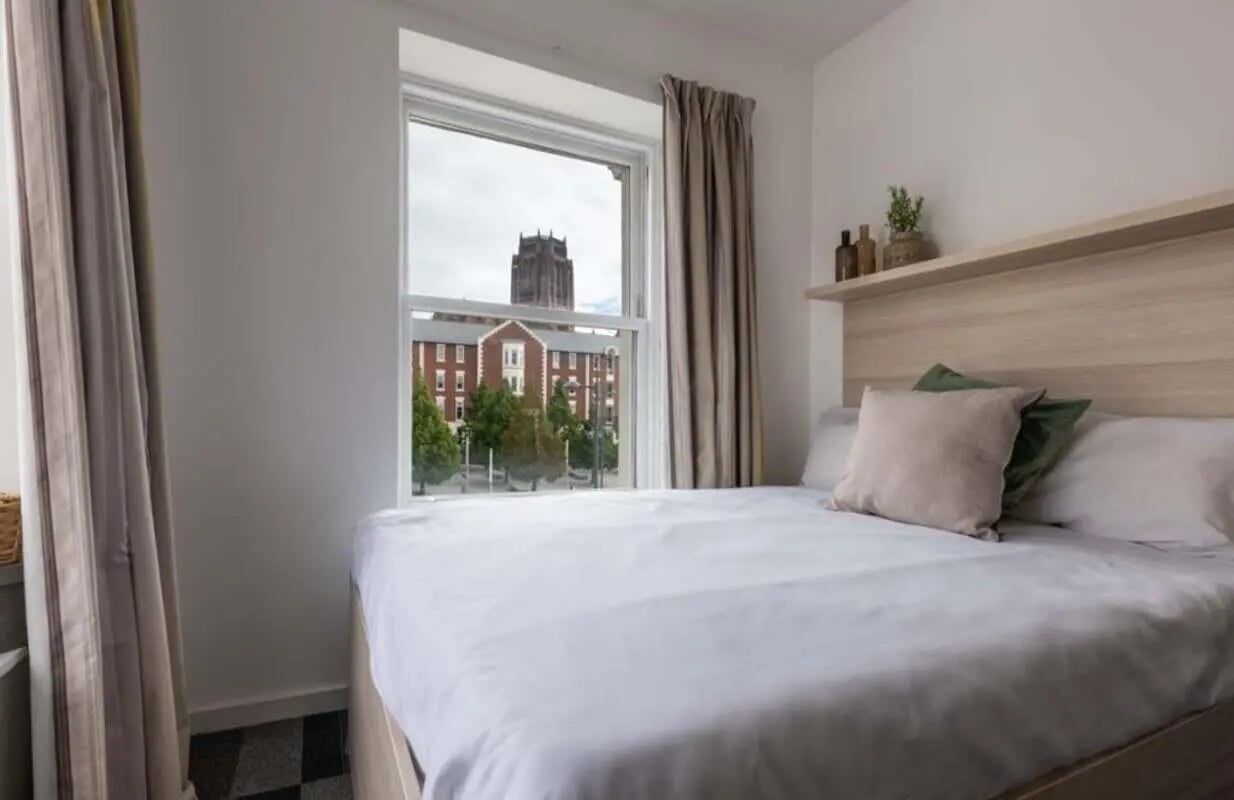 Bed with pillows near window overlooking buildings bedroom at The Arch - Liverpool in Liverpool Student Accommodation