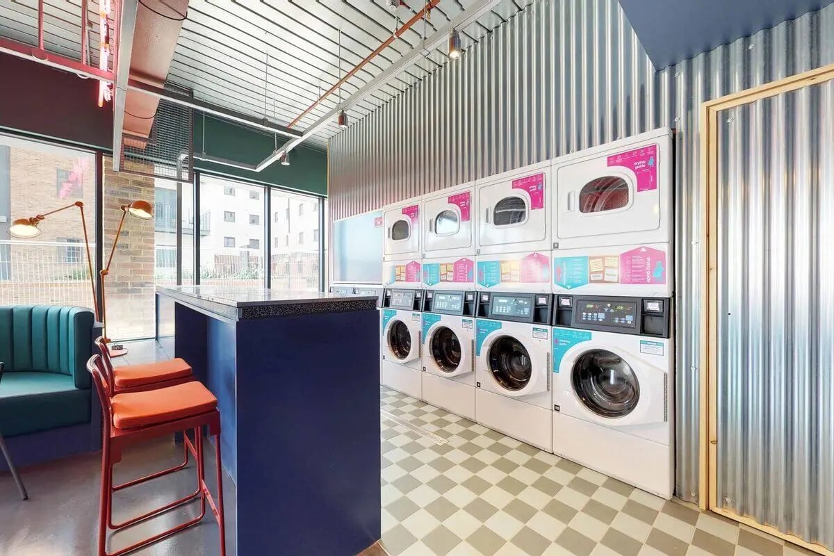 Stacked washing machines and dryers with a counter utility area at The Bridge in Newcastle Upon Tyne Student Accommodation