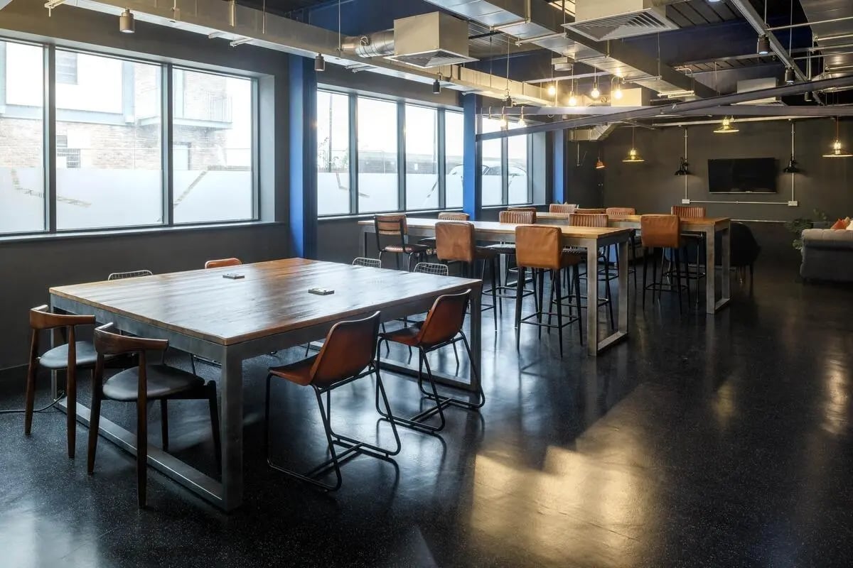 Wooden tables and chairs in a large common area. at The Bridge in Newcastle Upon Tyne Student Accommodation