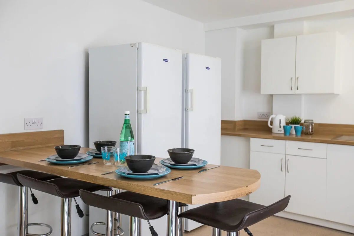 Two refrigerators breakfast bar with bowls kitchen at Rosedale Court in Newcastle Upon Tyne Student Accommodation
