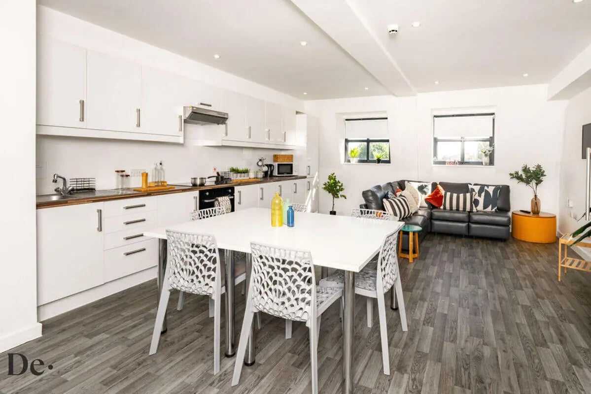 White table chairs kitchen cabinets and sofa living room at Castle Hill in Cambridge Student Accommodation