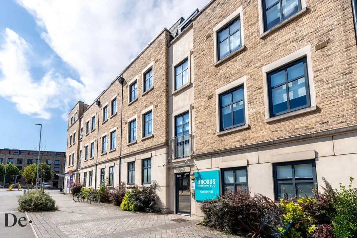 Brick building entrance with blue sign exterior at Castle Hill in Cambridge Student Accommodation